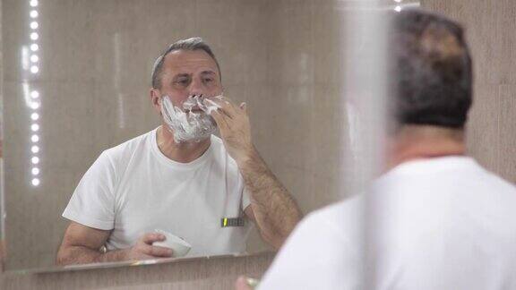 成熟英俊的男人在镜子前刮胡子