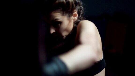 美丽的年轻女子在健身馆的沙袋在slowmotion拳击