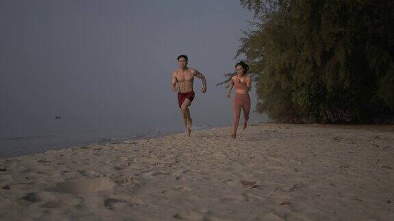 一对亚洲情侣在沙滩上慢跑
