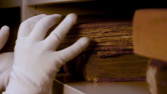 双手戴着白手套小心翼翼地放在书架上一本古书资料片仓库里有黄页的古书