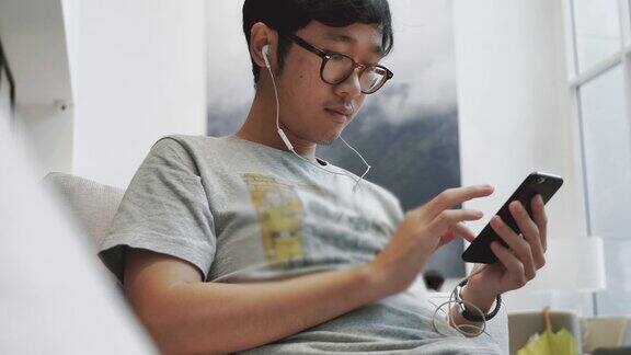 亚洲十几岁的男孩在手机上听音乐耳机