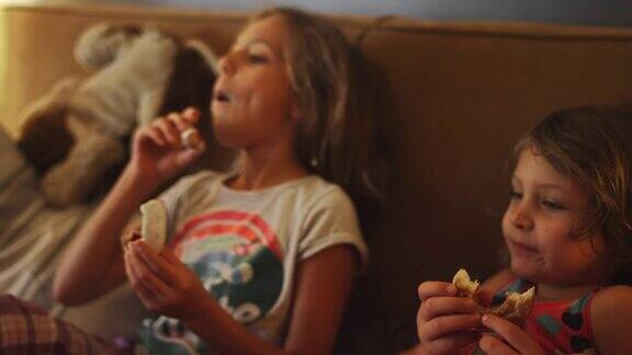 一个小女孩把一个甜甜圈放在她姐姐的脸上在她的鼻子上留下果冻