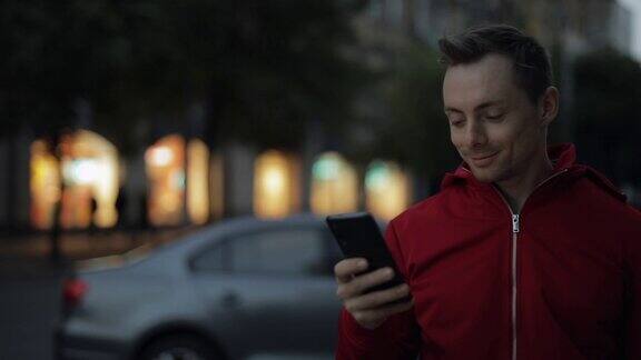 通过智能手机发短信的男人走在城市的街道上