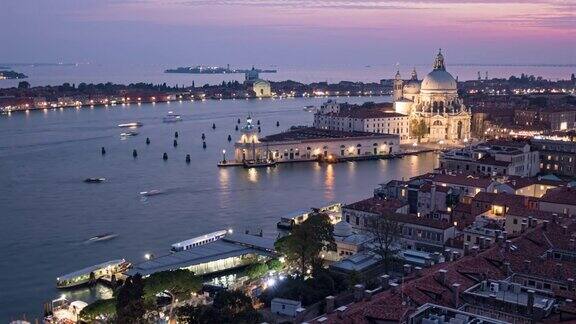 从意大利威尼斯的康帕尼勒俯瞰的大运河交通和圣玛丽亚德拉敬礼大教堂从白天到夜晚的空中过渡时间