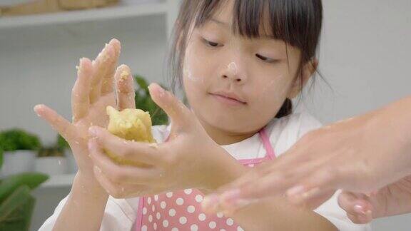快乐的亚洲孩子在家里一起学习做饼干女孩在她的手中打面团