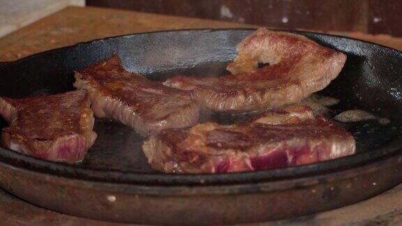 在铁锅里煎牛排这家餐厅的专业厨师在家做饭厨师把一块肉放在火上烤煎烟生肉蒸煮过程