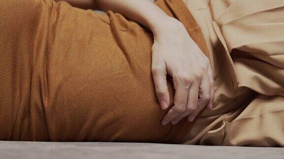 亚洲妇女有盆腔疼痛胃痛而躺在沙发上在家
