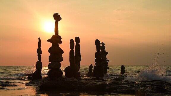 日落时分石像金字塔瑜伽概念海滩上海浪翻滚阳光反射在水面上美丽的黄昏自然海洋背景日落和日出