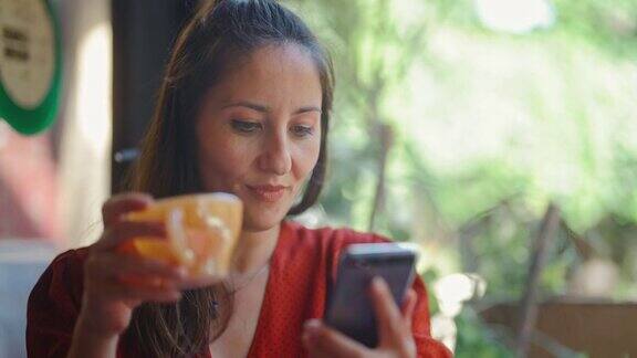 美女在咖啡馆喝着热饮用着智能手机