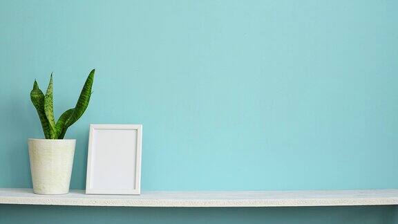 现代房间装饰与画框模型白色的架子靠在粉绿色的墙壁上手上放着一盆蛇草