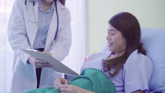 美丽聪明的亚洲医生和病人讨论和解释与医生手中的剪贴板而在病人的病床上在医院医学保健理念