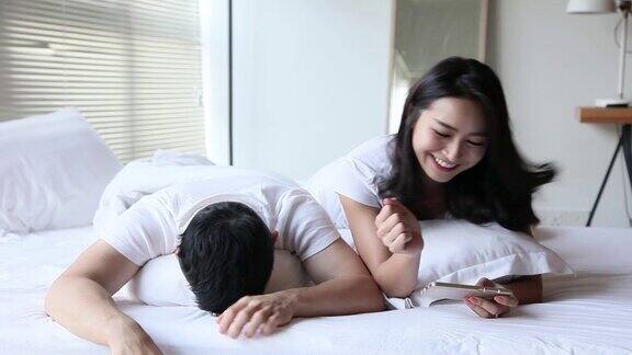 亚洲华人夫妇周末在卧室里玩手机游戏