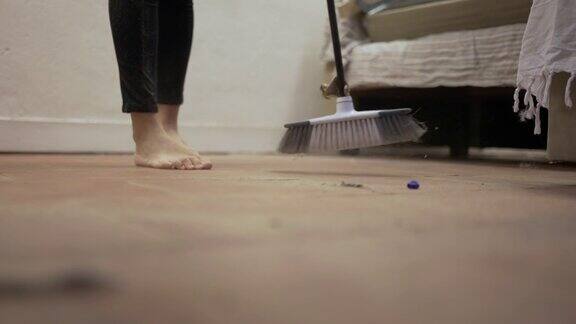 用扫帚扫脏地板的人做家务