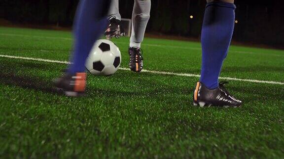 一名女子足球运动员晚上在对手铲球和防守时运球穿过球场