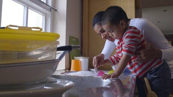 儿子帮妈妈在厨房水槽里洗碗