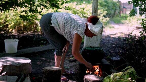 古老的乡村妇女在粘土炉上放干柴火