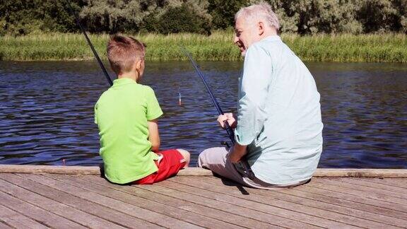 快乐的爷爷和孙子在河边钓鱼