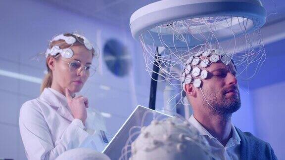女科学家在实验室通过脑电波扫描耳机检查男人的大脑
