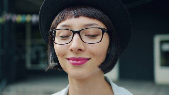 特写的年轻漂亮的女孩在眼镜和帽子微笑的户外