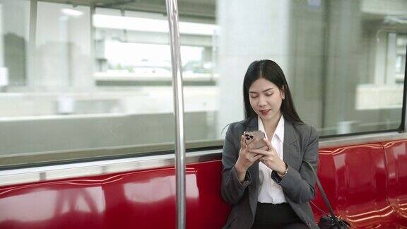 年轻的亚洲女商人在公共交通工具上使用智能手机在地铁里