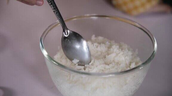 在玻璃碗里煮米饭的特写镜头厨师用勺子从碗里舀米饭