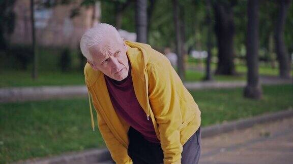 运动的老年男性在公园慢跑停下来喘口气运动