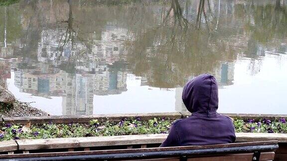 一个神秘孤独的男人坐在湖边的长椅上
