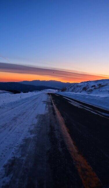 黄昏时分在雪山路上驱车驶向夕阳