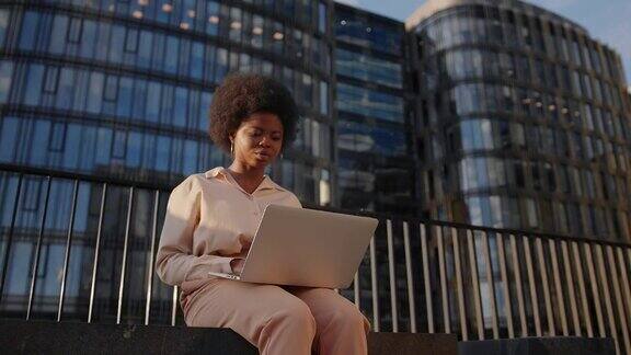 一位皮肤黝黑的年轻女企业家在她的笔记本电脑上对着商务中心写邮件