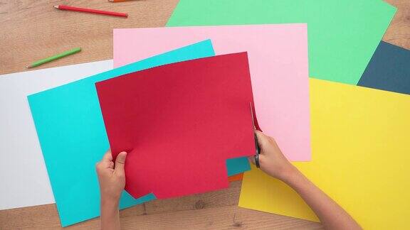 儿童用剪刀剪彩色纸从上到下的视图与彩色纸的桌子儿童学习、工艺、艺术
