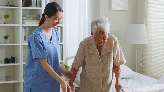 年轻的亚洲女性护士照顾者照顾者帮助和协助在家里使用手杖的亚洲老年妇女
