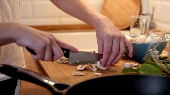 在桌子上切蘑菇的女人特写手在切菜板上切蘑菇年轻女子在厨房切蘑菇