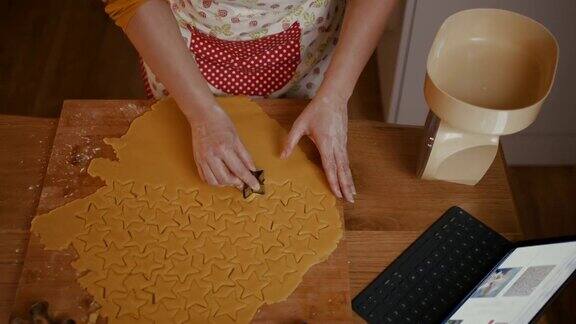 一个女人正在切面团做星星形状的圣诞饼干