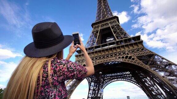 美丽的年轻女子用智能手机拍摄埃菲尔铁塔