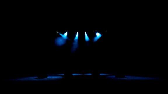 黑暗中空荡荡的音乐会舞台上的蓝色聚光灯