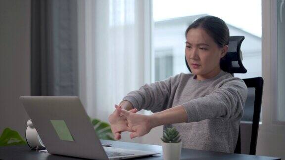 一名在家庭办公室使用笔记本电脑工作的亚洲女性身体疼痛