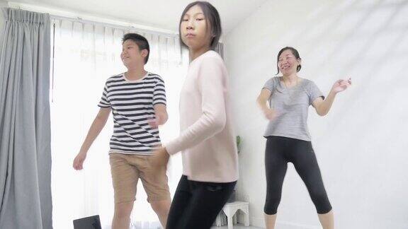 活跃的两个亚洲孩子和母亲学习如何跳舞在他们的客厅靠近窗户的一些空间在家里