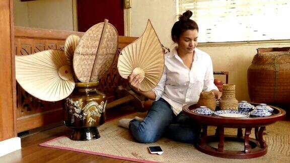 亚洲妇女用泰国传统的竹制硬扇住在古老的木屋里