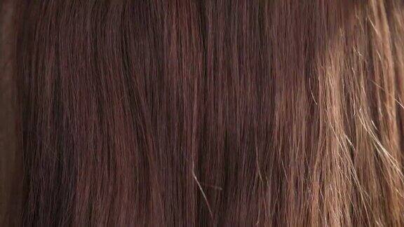 女性手梳理长美丽健康流动的棕色头发特写阳光照耀纹理