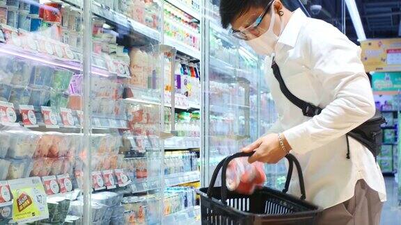亚洲男人戴着面具保护和他在超市购物