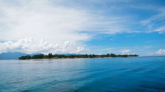 在一个有许多树木和绿色植物的小岛上从船上看位于一个蓝色的海洋那里有一个清澈的蓝天和云