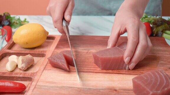女人的手正用刀在切板上切切生金枪鱼用金枪鱼做一顿饭