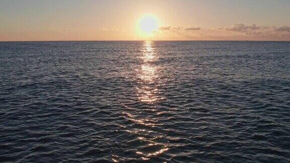 日出时海面上的海浪反射出天空的蓝色和橙色