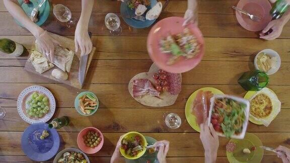 朋友们在餐桌上传递食物在头顶上用R3D拍摄