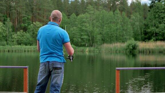 一名身穿蓝色t恤的男子在河边钓鱼