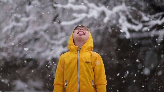 穿着黄色冬衣的滑稽小男孩在下雪时行走儿童冬季户外活动