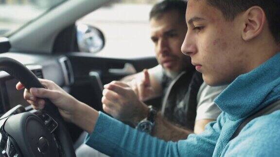 一个十几岁的男孩和一个男老师一起上驾驶课
