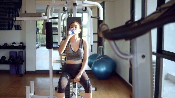 亚洲女人在健身房喝能量饮料