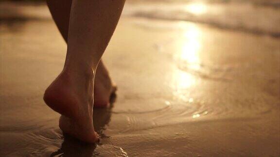 美丽的场景一个低段的女人走在海边的日落