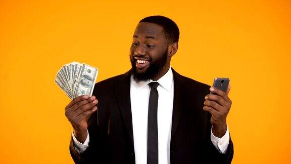 非裔美国男人穿着西装拿着手机和钞票拿着现金